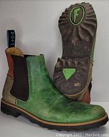 Side and bottom view of green leather Chelsea boots showing overall style, colors, and sole tread.