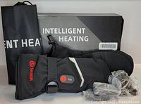 Pair of black Savior Intelligent Heating heated mittens, packaging box, storage bag, and accessories shown on a flat surface.