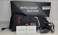 Photo showing the black XS Savior heated glove with the box labeled 'INTELLIGENT HEATING', two battery packs labeled 'Battery Pack', and a charger cable.