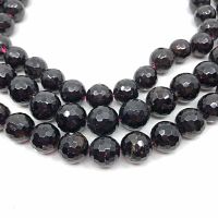Close-up of the faceted round garnet beads on the strands showing the dark red polished surface and facets.