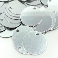 Close-up of round aluminum stamping blanks showing smooth shiny surface and punched hole near the edge.