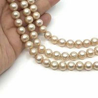 Close-up of three strands of round champagne pearls held in hand showing surface texture and luster.