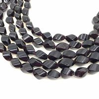 Close-up image of several garnet beads showing twist cut and polished surface in dark red color.