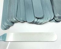 Stack of approximately 71 aluminum bracelet blanks showing rounded edges and blue protective film, with one blank partially peeled to display shiny surface underneath.