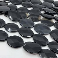 Faceted oval black onyx beads laid flat
