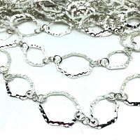 Close-up of hammered silver-colored links with irregular geometric shapes showing the textured hammered surface.