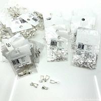 Various sealed bags of silver plated bails and rings with some loose pieces displayed in front showing shape and size.