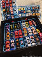 Top angled view of 48 Hot Wheels cars arranged in a blue plastic storage case with compartments for each car.