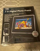 Box of TDE Systems 7 inch digital photo frame with image of frame displaying colorful digital picture, showing USB and SD card compatibility, and remote control features.