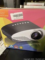 Front of the projector box showing image of the black and white projector and basic product category information.