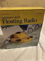 Original box of the Realistic Waterbuddy AM/FM Floating Radio, yellow floating boat-shaped radio with control knobs visible in the photo.
