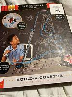 Front of the box showing product name, brand, motorized feature, piece count, and an image of the assembled coaster with a boy playing.