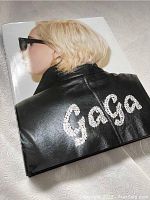 Front cover of the hardcover book showing Lady Gaga in a black leather jacket with GaGa in sequins on the back.