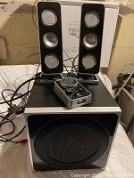 Full set showing Logitech Z4 subwoofer, two satellite speakers, and wired control unit on top of the subwoofer with attached cables.