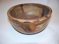 Side perspective of brown ceramic bowl showing shape, glaze color, and decorative dark streaks.