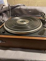 Front-right angle of turntable showing platter, wood plinth and open dust cover
