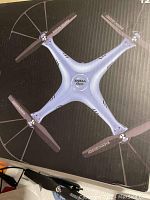 Top-down view of Syma X5HC-1 drone on packaging box showing silver quadcopter with four propellers and guards.