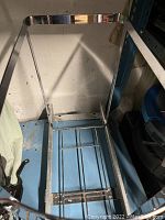 Overall front view of the chrome waste frame on wheels showing rectangular structure and base crossbar.