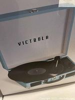 Photo of the Victrola Journey suitcase record player box showing a light blue portable record player with Bluetooth feature.