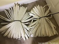 Two lengths of white fire hose folded flat and bundled with ties, laid on floor.