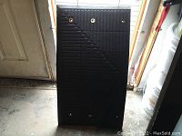 Three black rubber heavy duty industrial floor mats stacked upright, showing the textured surface and metal grommet holes for bolting.