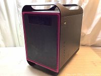 Front and side view of black Asus ROG Maximus computer tower frame showing red trim and ventilation grille with fan behind it.