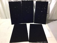 Five black velvet jewelry display panels shown vertically and horizontally, with visible golden hooks on some panels, panels are blank without jewelry.