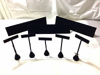 Nine black velvet jewelry display stands and panels on white surface against white backdrop. Five T-bar stands with weighted bases and four rectangular earring panels, varying sizes.