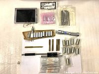 Overview of lot showing micrometer tool parts, calibration rods, metal sleeves, and a standard bar