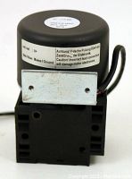 Side view of black square base pump with attached cylindrical motor housing and metal mounting bracket, showing label with caution text.