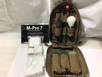 Zippered carrying case with cleaning patches, brushes, and instruction manual laid out inside.