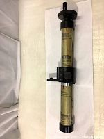 Full view of the industrial precision tool wrapped in KS VCI Ferobrite SS film, showing cylindrical shape and attached black metal components.