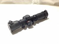 Full view of the matte black Tact 100 crossbow scope showing body, lens cover, and one mounting ring.