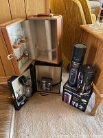 Photo showing tan portable bar case with glasses inside, black portable bar case open with bar tools, and boxed electric beverage accessories (Electric Rabbit, Vinturi, Zerowater).