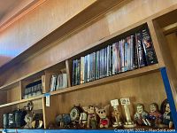 Top wood shelves filled with DVDs, CDs, radio boombox, dog and other decorative figurines, and various small accessories.