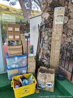 Full view of all items including garden reed fencing rolls, boxes, plastic bins, garden tools and garden accessories.