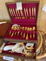 Two-tier wooden chest open to show all flatware pieces arranged in velvet-lined trays