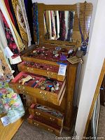 Front view of oak jewelry box with mirror and three drawers open, showing contents