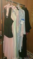 Clothes rack showing eight sleepwear items including nightgowns and robes in pastel colors and black, multiple lace and satin fabrics visible.