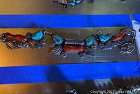 Full length view of the silver link necklace laid out on a surface with blue tape border.