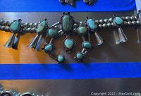 Full view of silver bead necklace with ten squash blossom pendants and central naja pendant set with turquoise stones