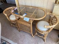 Front‐angle overview showing oval glass‐top table and two swivel chairs