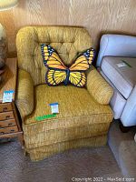 Front view of the yellow upholstered sofa rocker chair with tufted backrest and a butterfly pillow on the seat.