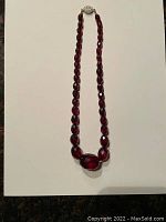 Full view of the necklace showing faceted cherry red beads and larger central bead.