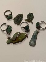 Eight items arranged on white surface: four rings and four pendants