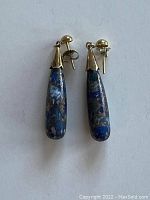 Pair of tear-drop shaped earrings laid flat on white background