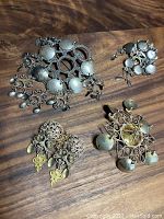 Four antique silver Norwegian marriage brooches arranged on wood background showing various sizes and styles with filigree and dangling discs