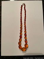 Full view of the graduated amber bead necklace laid on white background