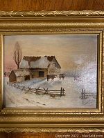 Overall front view of the framed oil painting showing barn, fence and cattle in snow