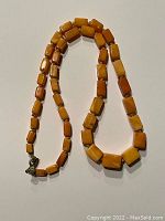 Full view of necklace laid out showing cubed amber beads and metal clasp